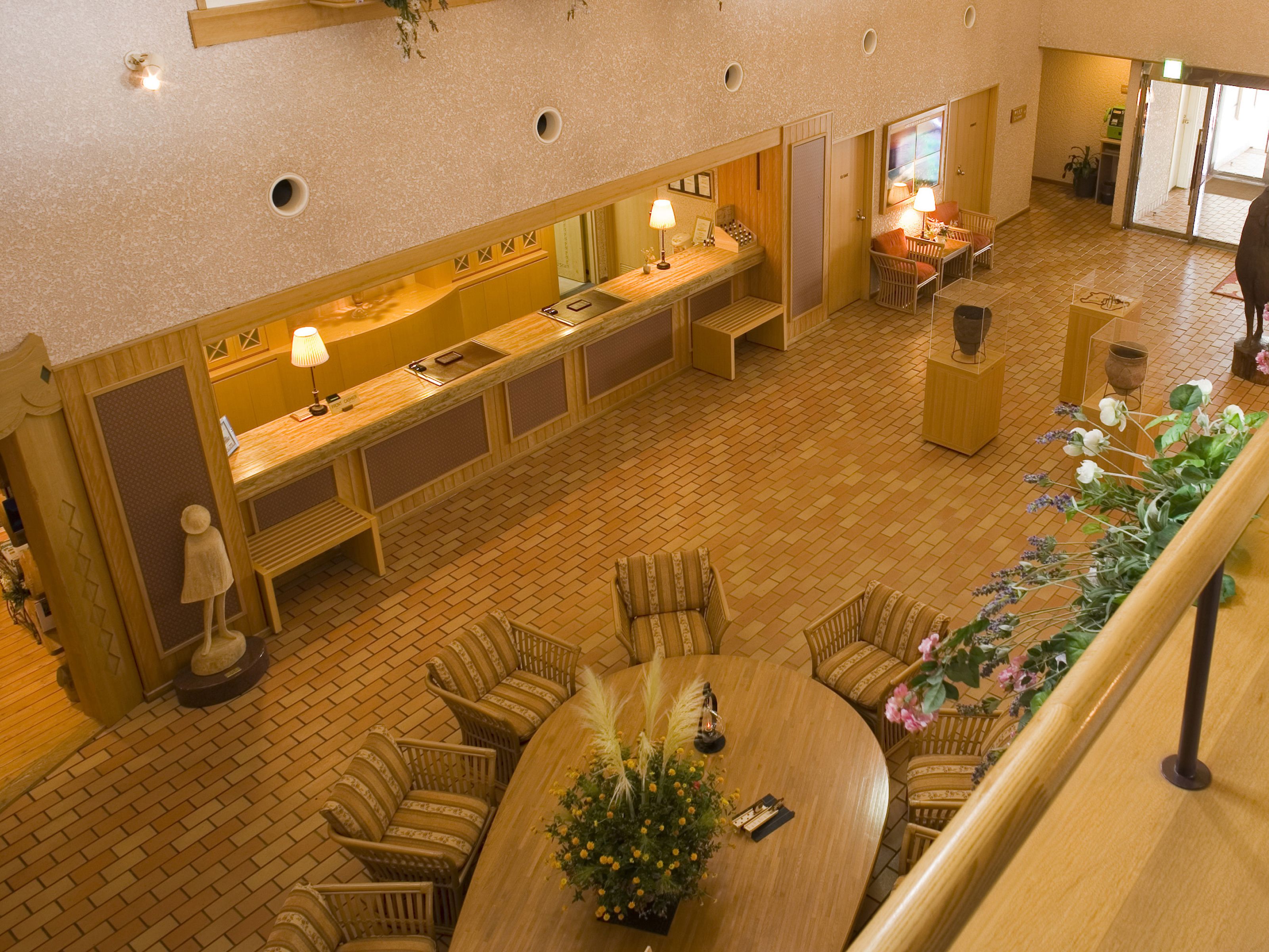 Un hall de hotel con mostrador de recepción, zona de estar y una escalera.