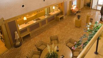 Un hall de hotel con mostrador de recepción, zona de estar y una escalera.