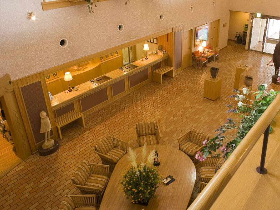 Un hall de hotel con mostrador de recepción, zona de estar y una escalera.