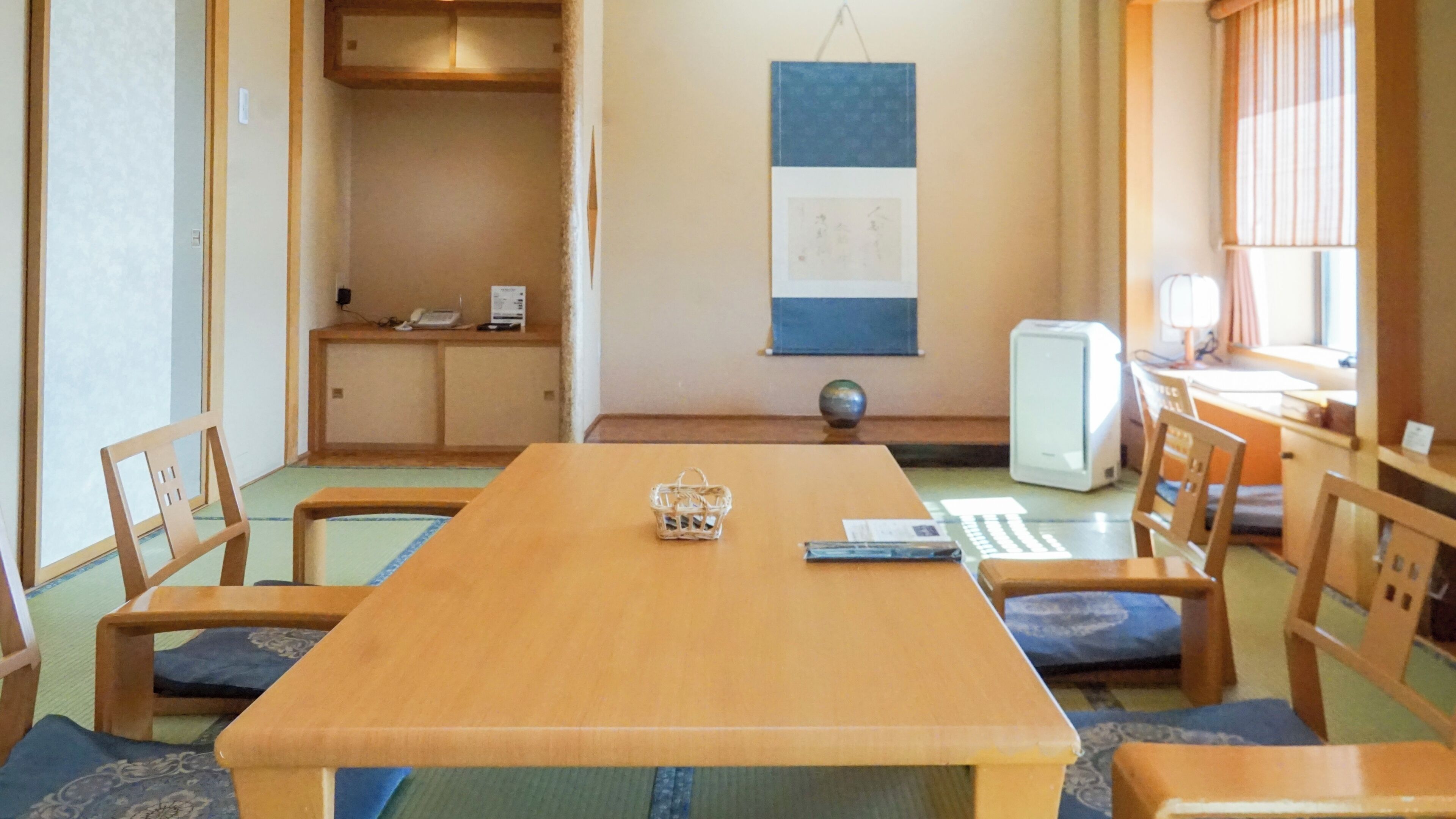 Una habitación tradicional japonesa con suelo de tatami, una mesa de madera baja y muebles de madera sencillos.