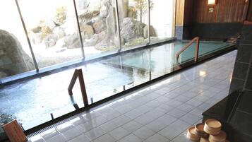 A spa area with a glass-enclosed hot tub, tiled floor, and wooden steps leading to a seating area.