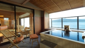 Un área de spa con un jacuzzi, mobiliario de madera y vistas a un lago.