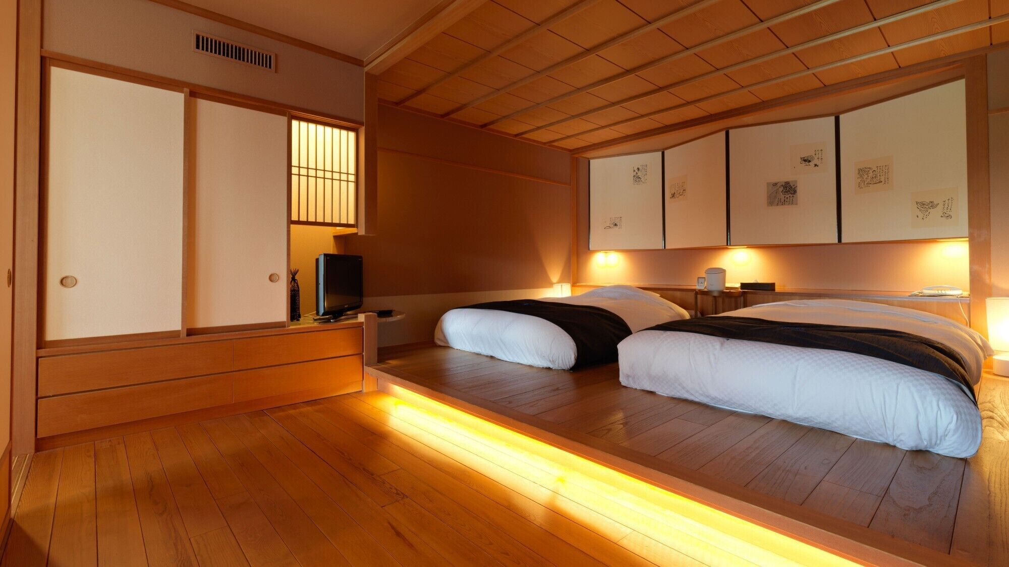 A traditional Japanese-style room with a low platform bed, wooden flooring, sliding doors, and a television.