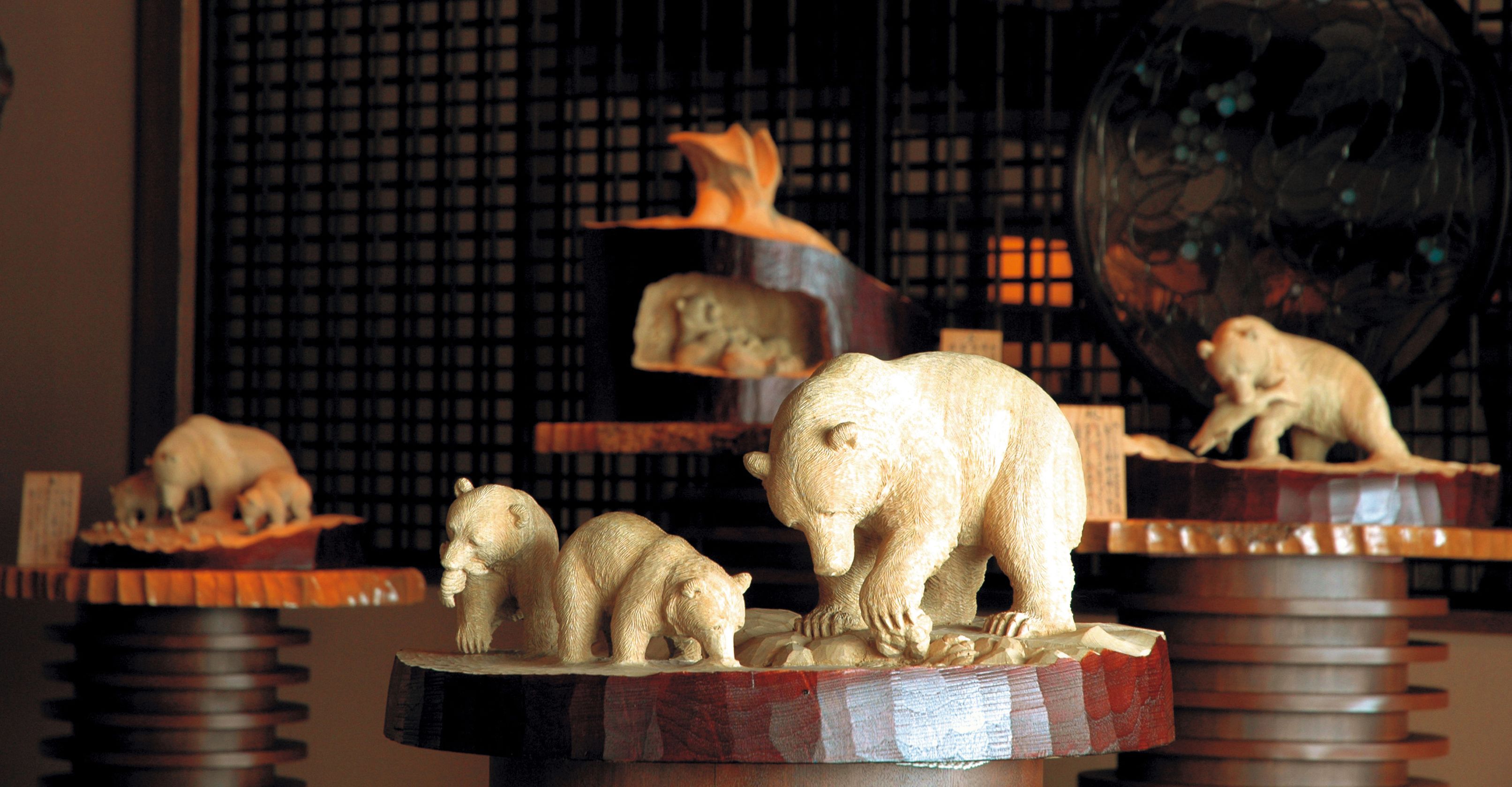 Una exhibición de figuras de animales de madera sobre una estantería.