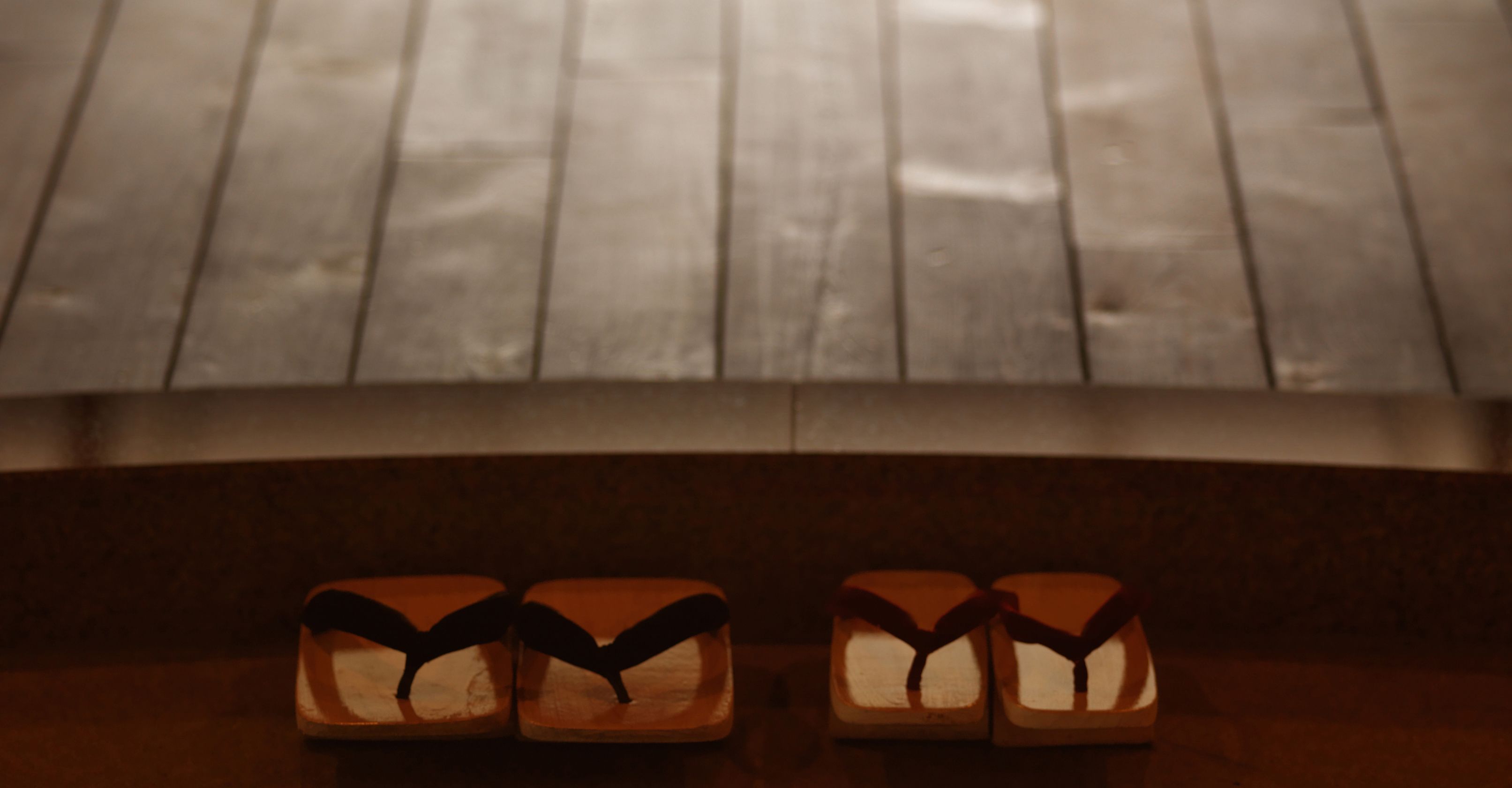 A pair of wooden sandals with black straps on a wooden surface.