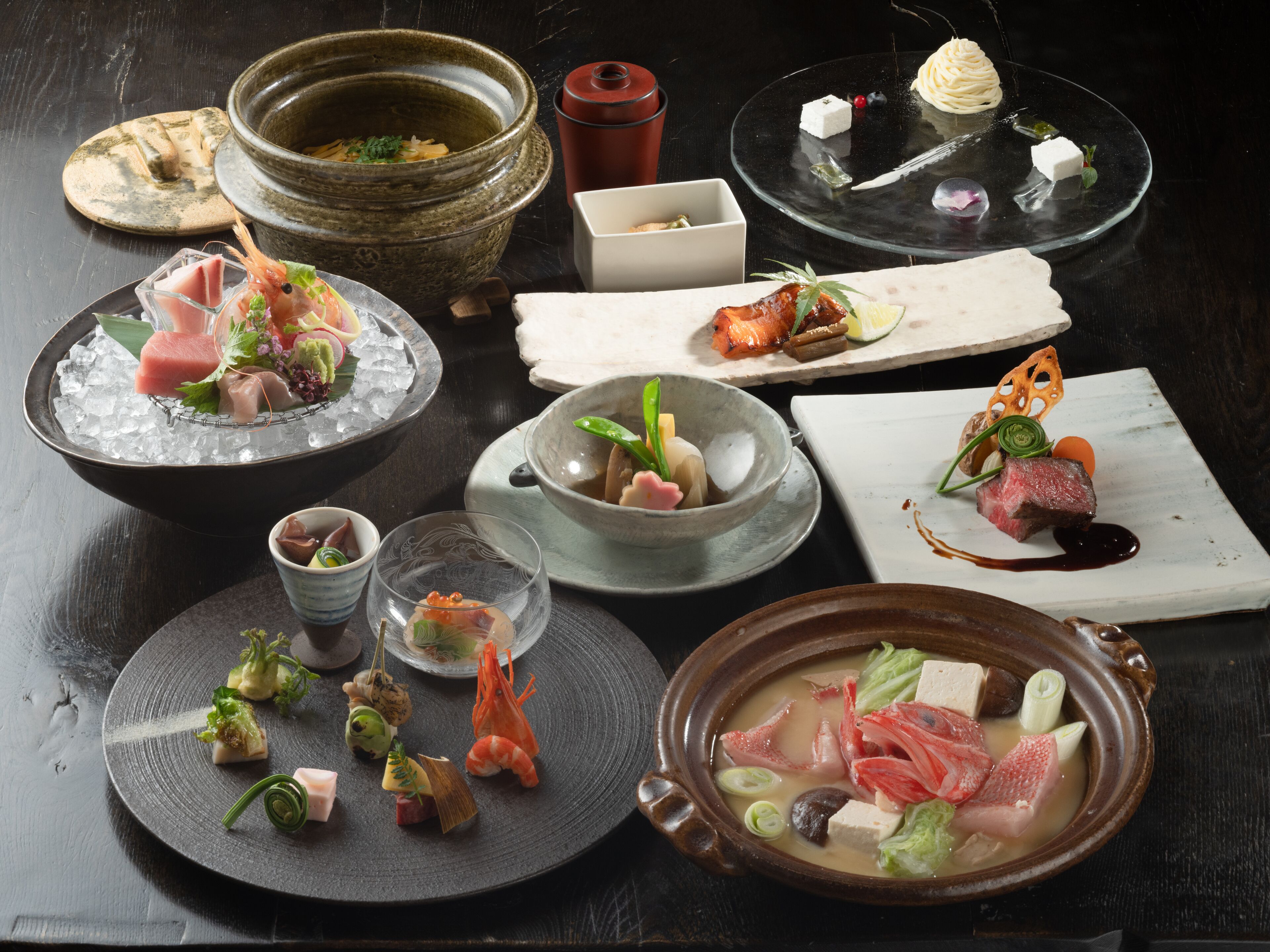 A variety of dishes on a table, including sushi, sashimi, and a bowl of soup.