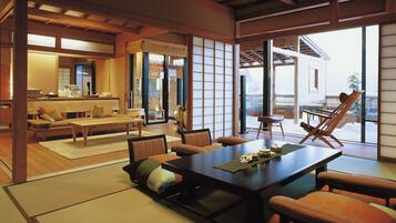 A traditional Japanese-style room with tatami flooring, a low table with cushions, and sliding doors leading to a balcony with a view of a snowy landscape.