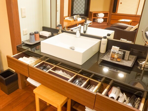 Une salle de bain moderne avec un grand lavabo blanc, un miroir et un meuble-lavabo doté de nombreux tiroirs et d’un banc.