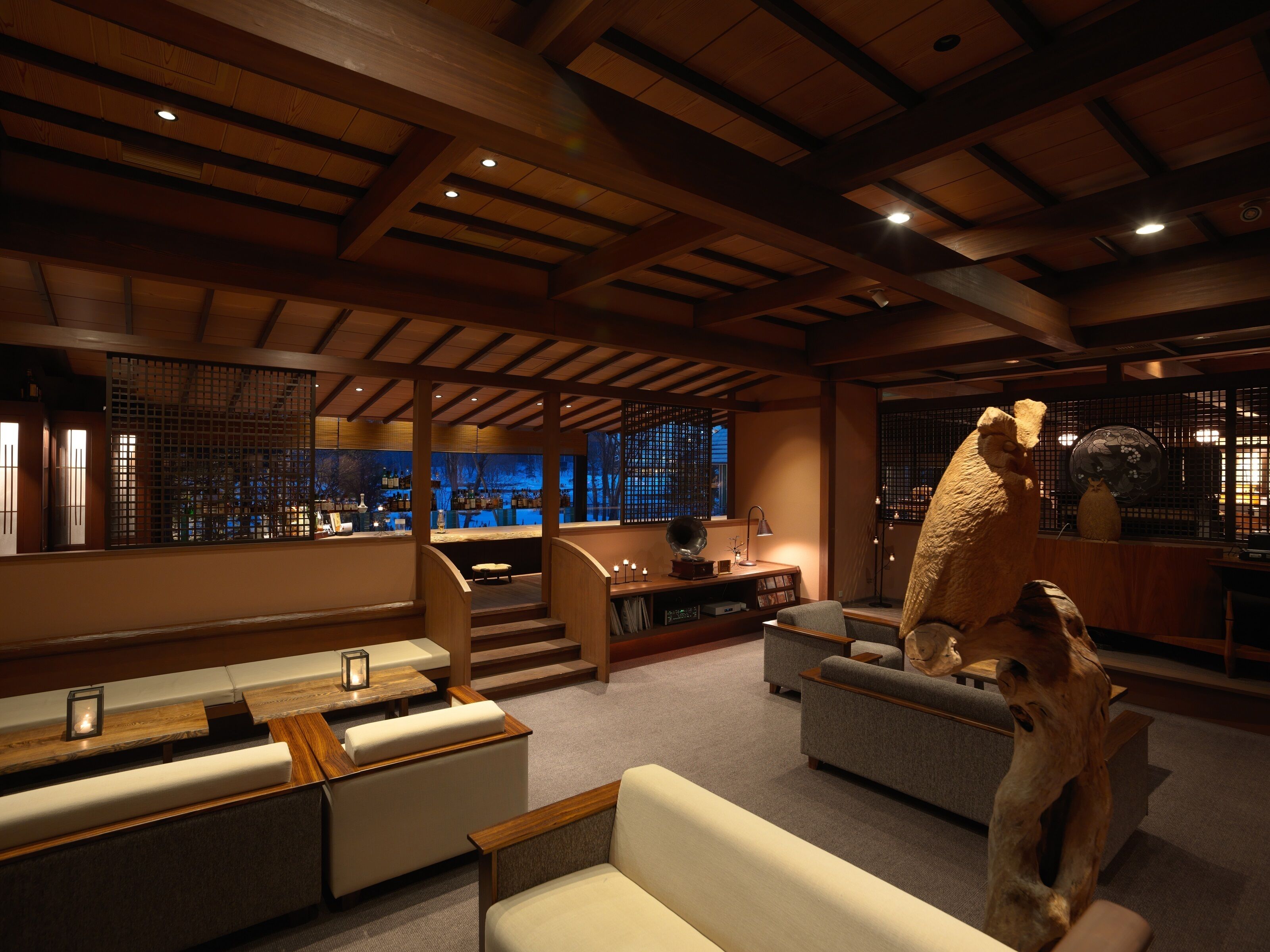 A spacious room with a high ceiling, wooden beams, and a seating area with sofas and a coffee table.