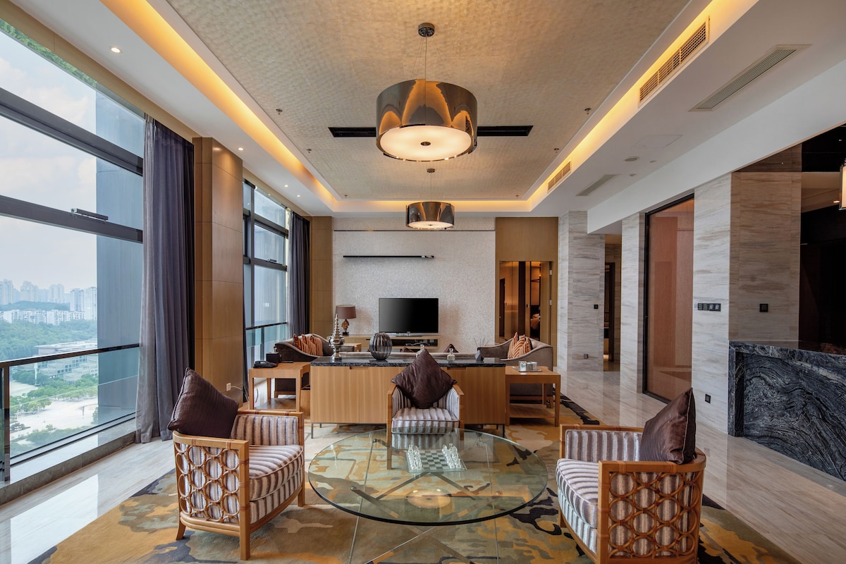 A spacious living area with a large TV, comfortable seating, and a view of the city.