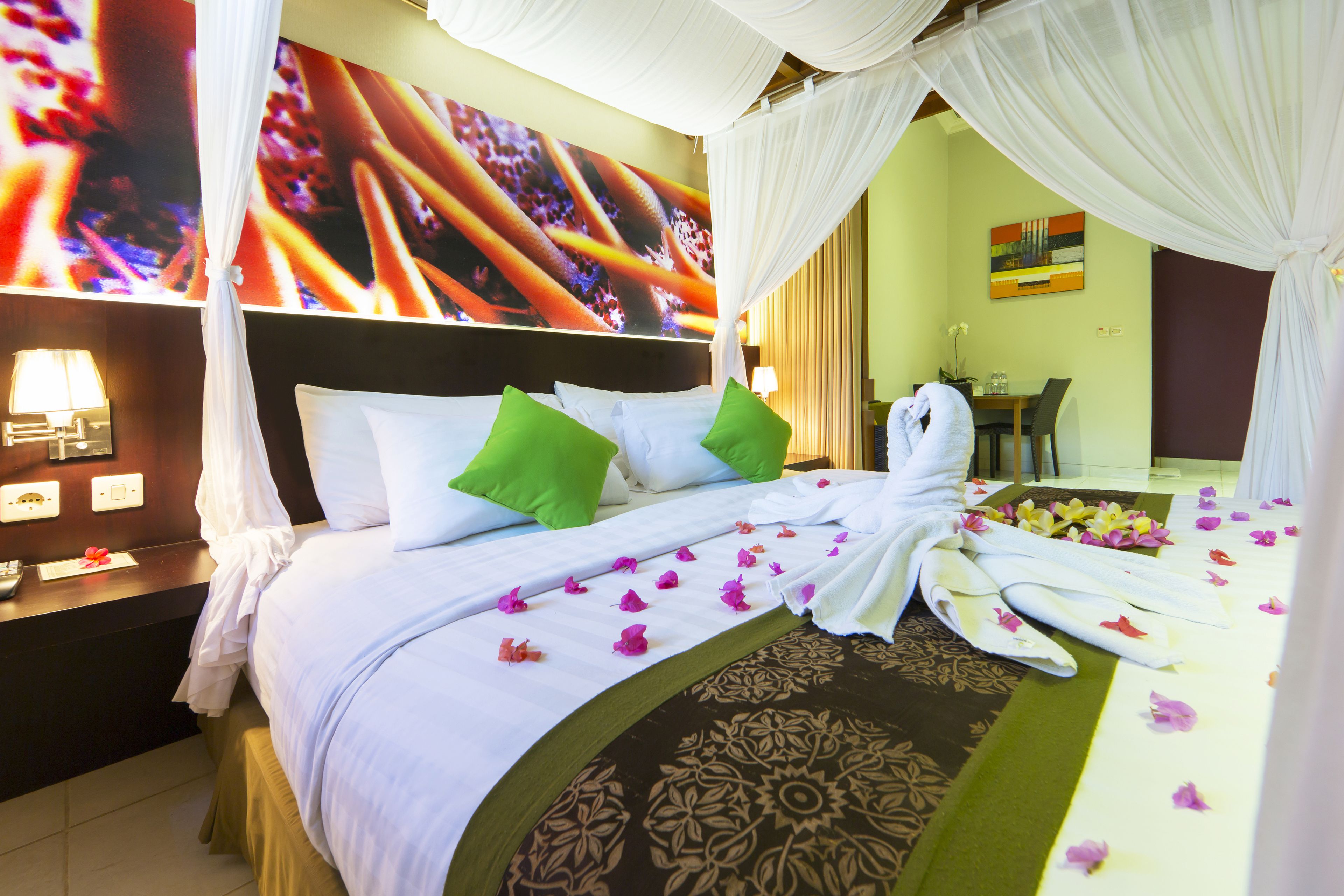 Une chambre d’hôtel avec un lit, des oreillers verts, une grande couvre-lit et un baldaquin.