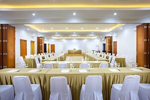 A conference room with long tables, white chairs, and a stage.