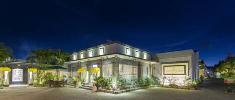 A hotel with a paved courtyard, outdoor seating area, and a sign reading "The Banyumas Villa".