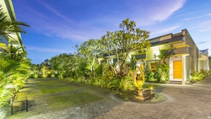A modern building with a well-maintained garden, paved pathways, and a bench. - The Banyumas Villa (Denpasar)