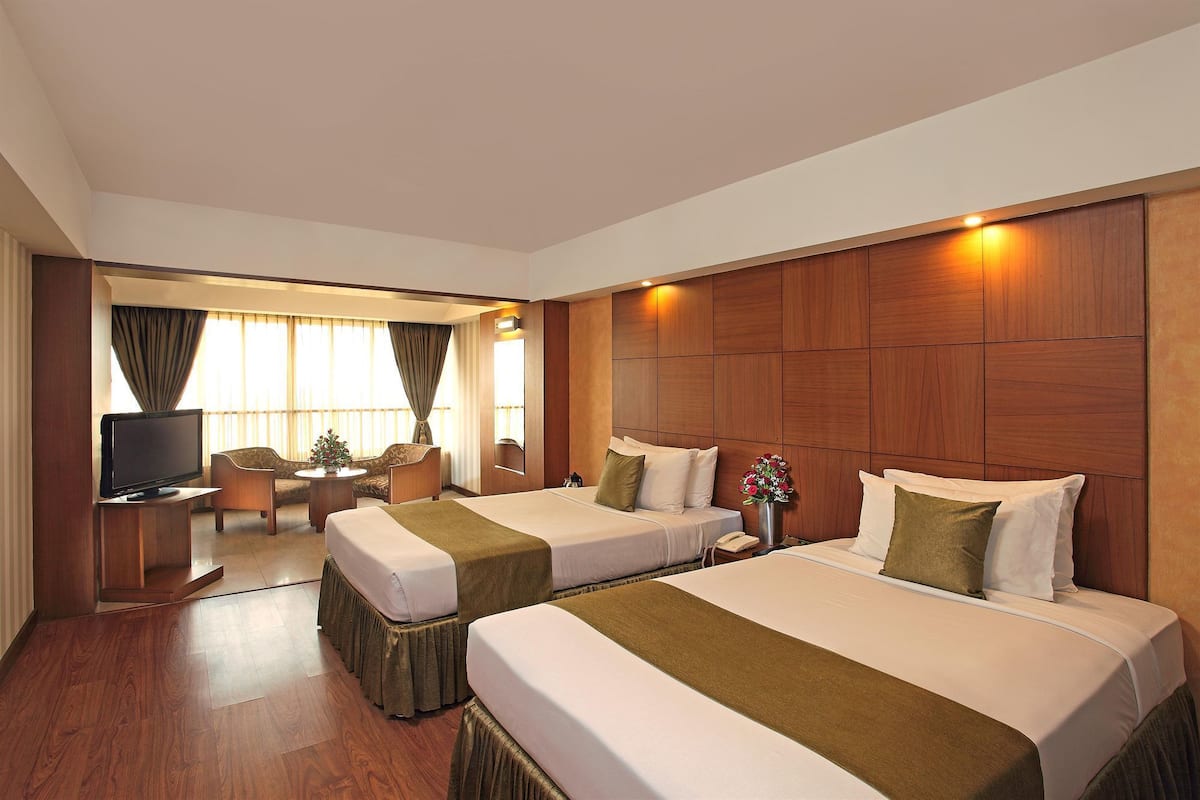 A hotel room with two beds, a TV, a desk, and a chair.