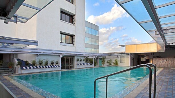 Una piscina interior con agua azul cristalina, rodeada por una solana con baldosas y una zona cerrada con cristales.