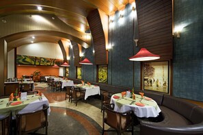 A restaurant with tables set for dining, wooden paneling on the walls, and artwork on the walls. - Hotel Aurora Towers (Pune)