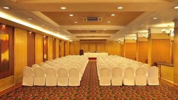 A conference room with rows of white chairs, a long table, and a carpeted floor.