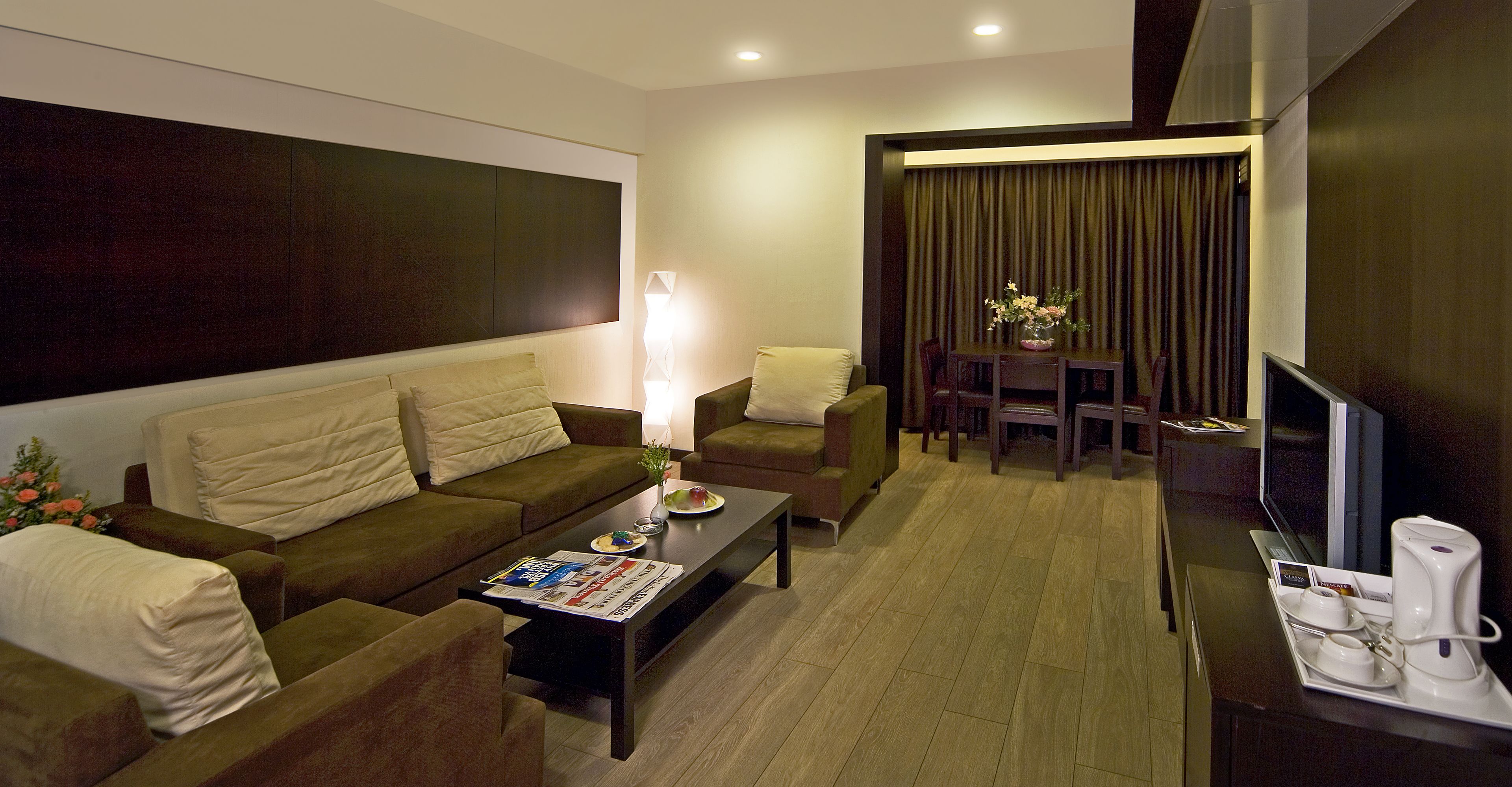A modern living room with a sofa, armchairs, a coffee table, and a TV.