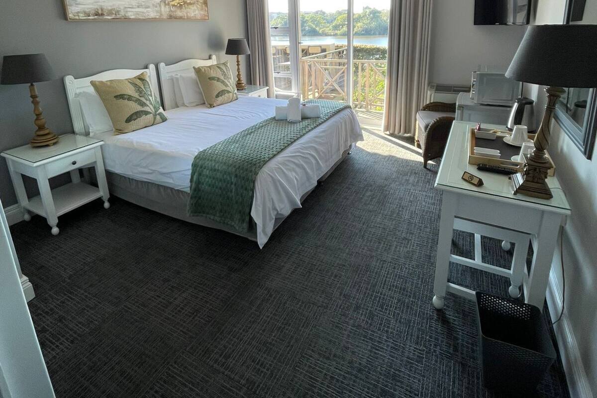 Une chambre d’hôtel dotée d’un grand lit, de deux tables de chevet, d’un bureau avec une chaise, d’un téléviseur à écran plat et d’un balcon offrant une vue sur l’extérieur.