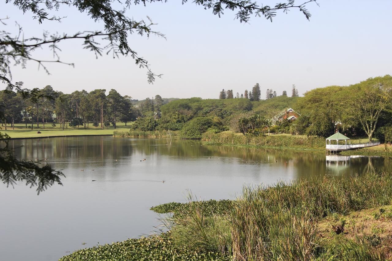 A serene lake with a gazebo and a small building in the background.