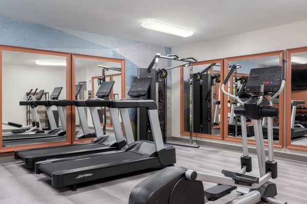 Ein Fitnessstudio mit Laufbändern, Crosstrainern und Kraftgeräten.