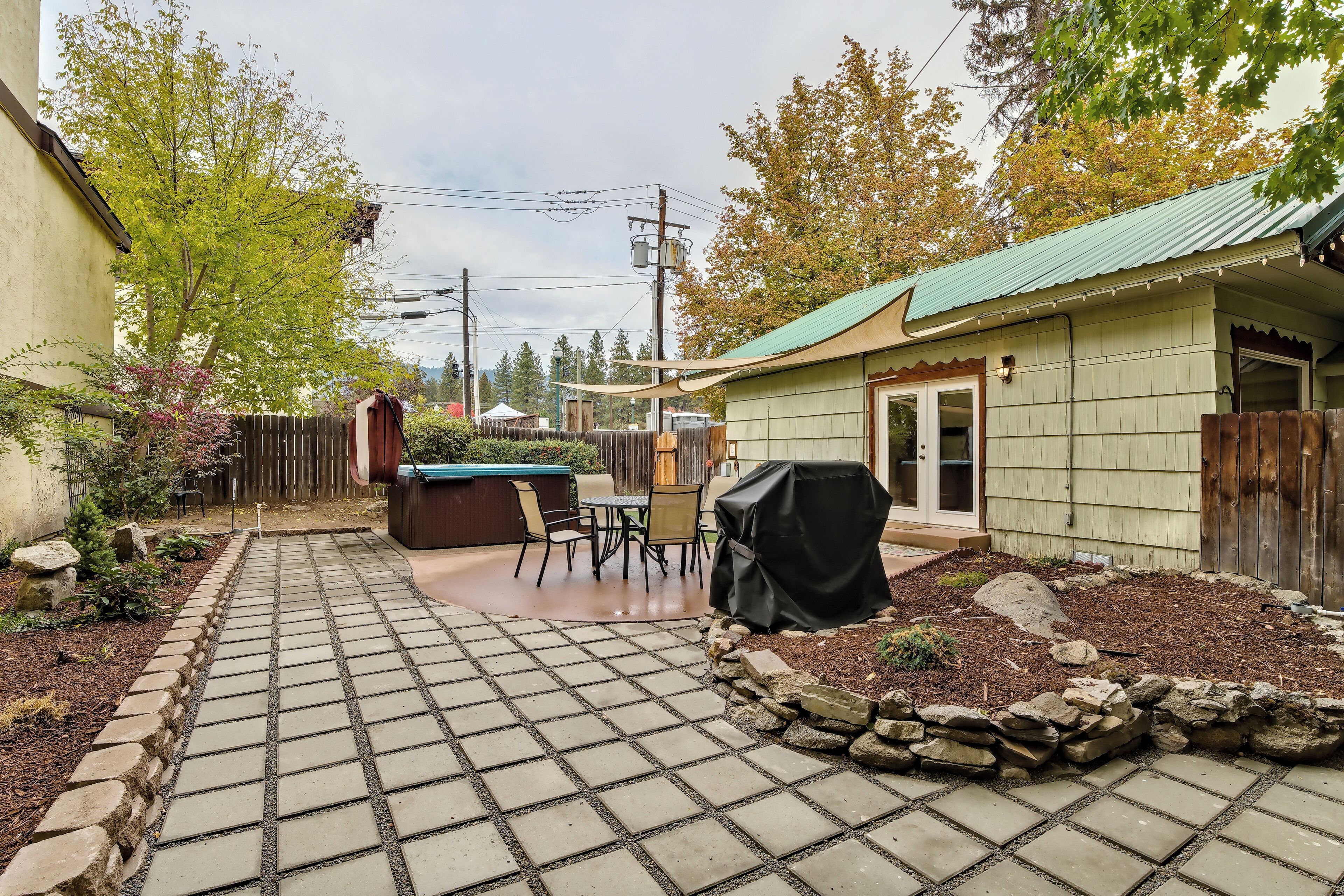 A backyard with a patio, outdoor seating, a barbecue grill, and a shed.