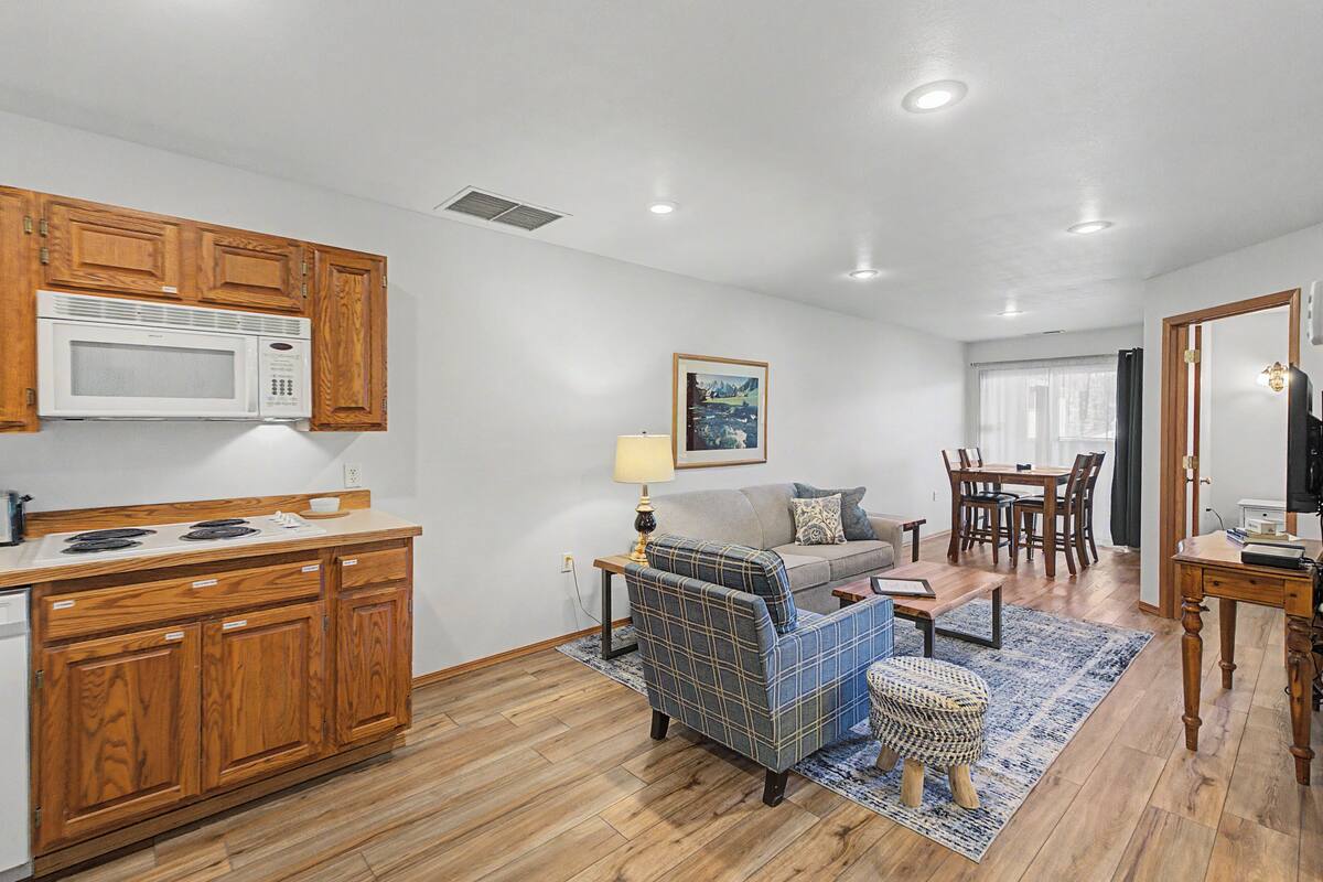Un espacio habitable compacto con kitchenette, un sofá, una mesa de comedor y un televisor.