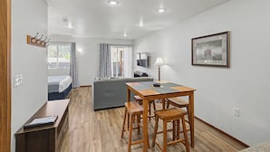 A compact living space with a kitchenette, a sofa, a dining table with chairs, and a television. - Obertal Inn (Leavenworth)