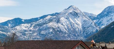 A mountain landscape with snow-covered peaks and a village with traditional architecture.