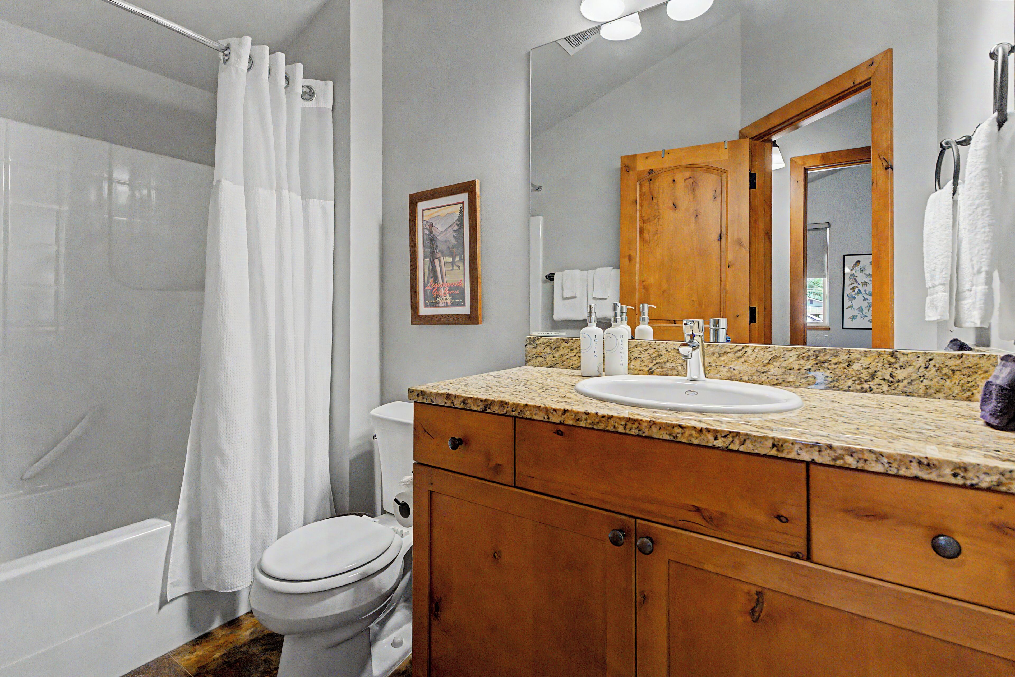 Ein Badezimmer mit Dusche, Toilette, Waschbecken und Holz-Badmöbel.