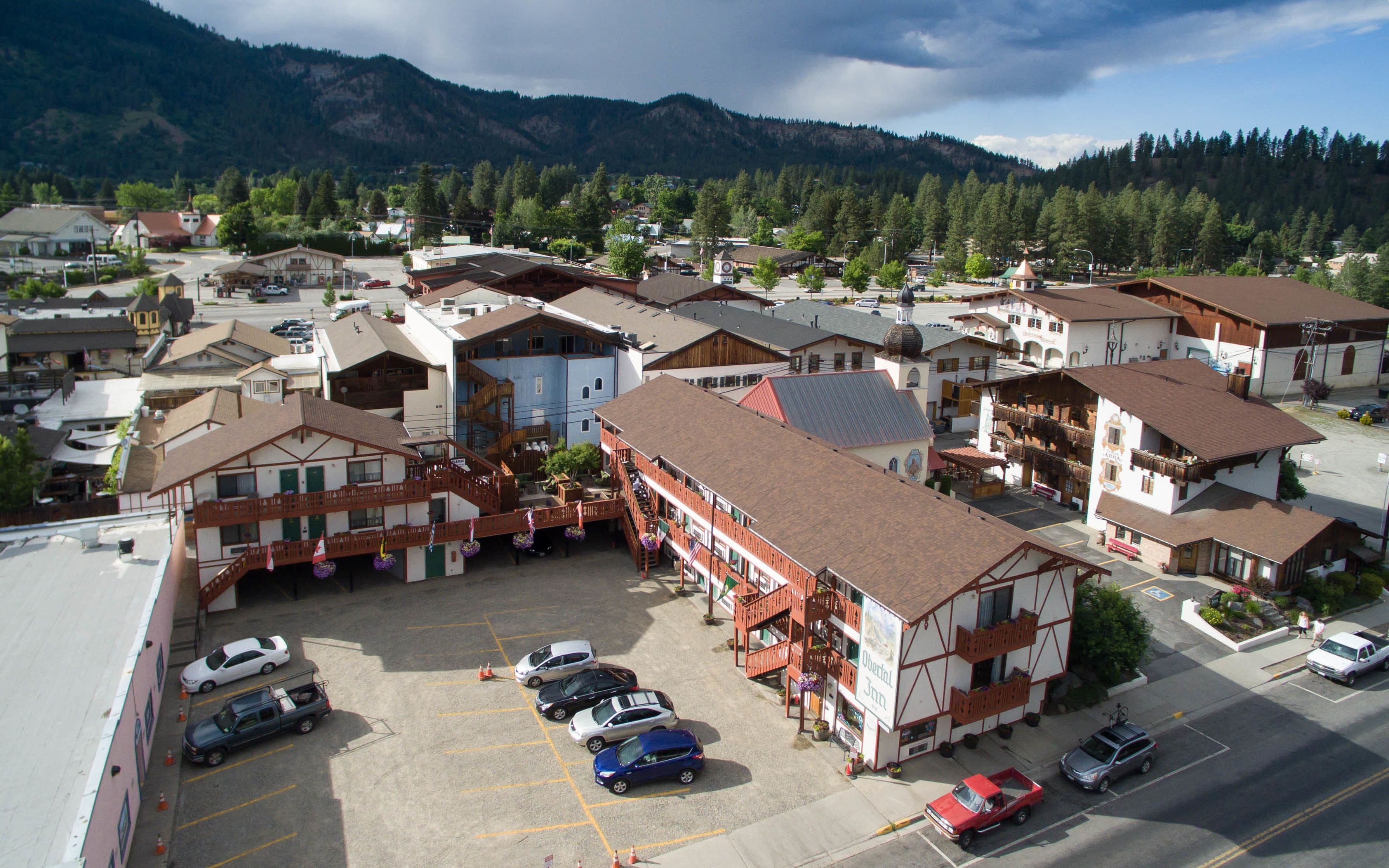 A hotel with a central courtyard, multiple balconies, and a mountain backdrop.