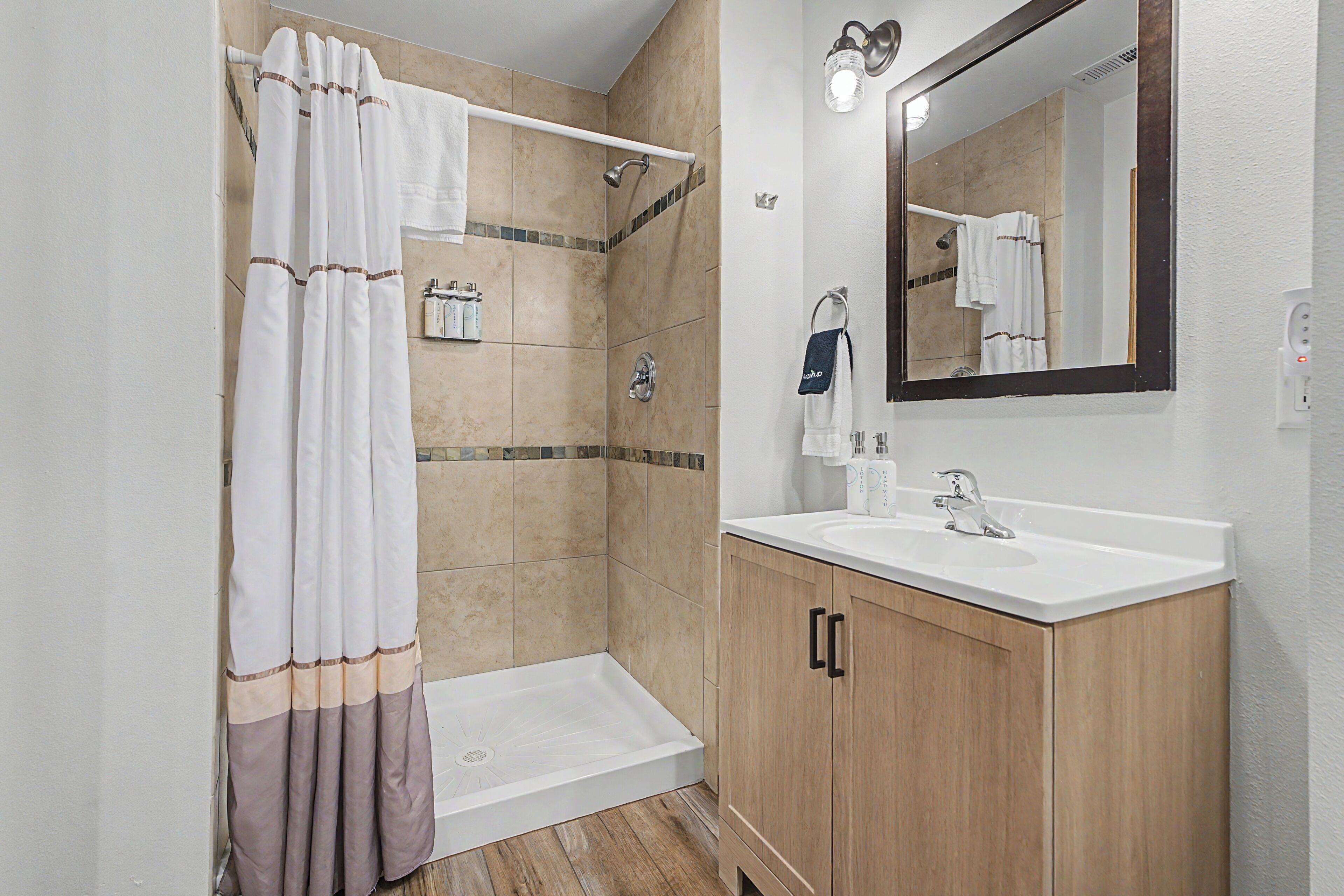 A modern bathroom with a shower, a sink, and a mirror.