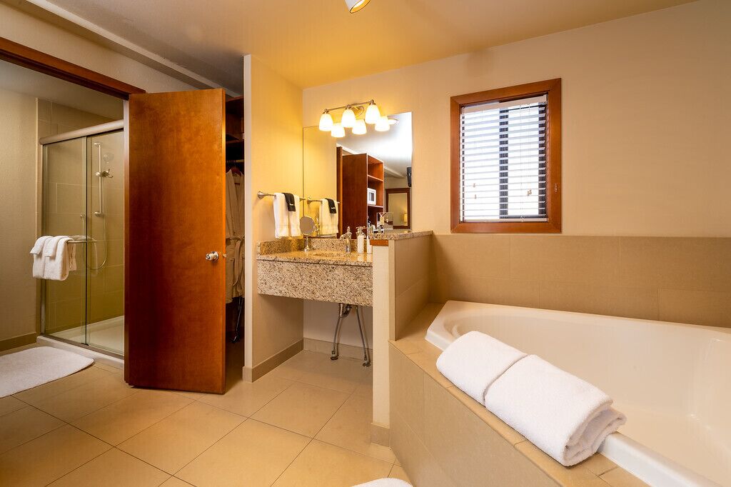 A modern bathroom with a glass shower, a vanity with a sink, a bathtub, and a large mirror.