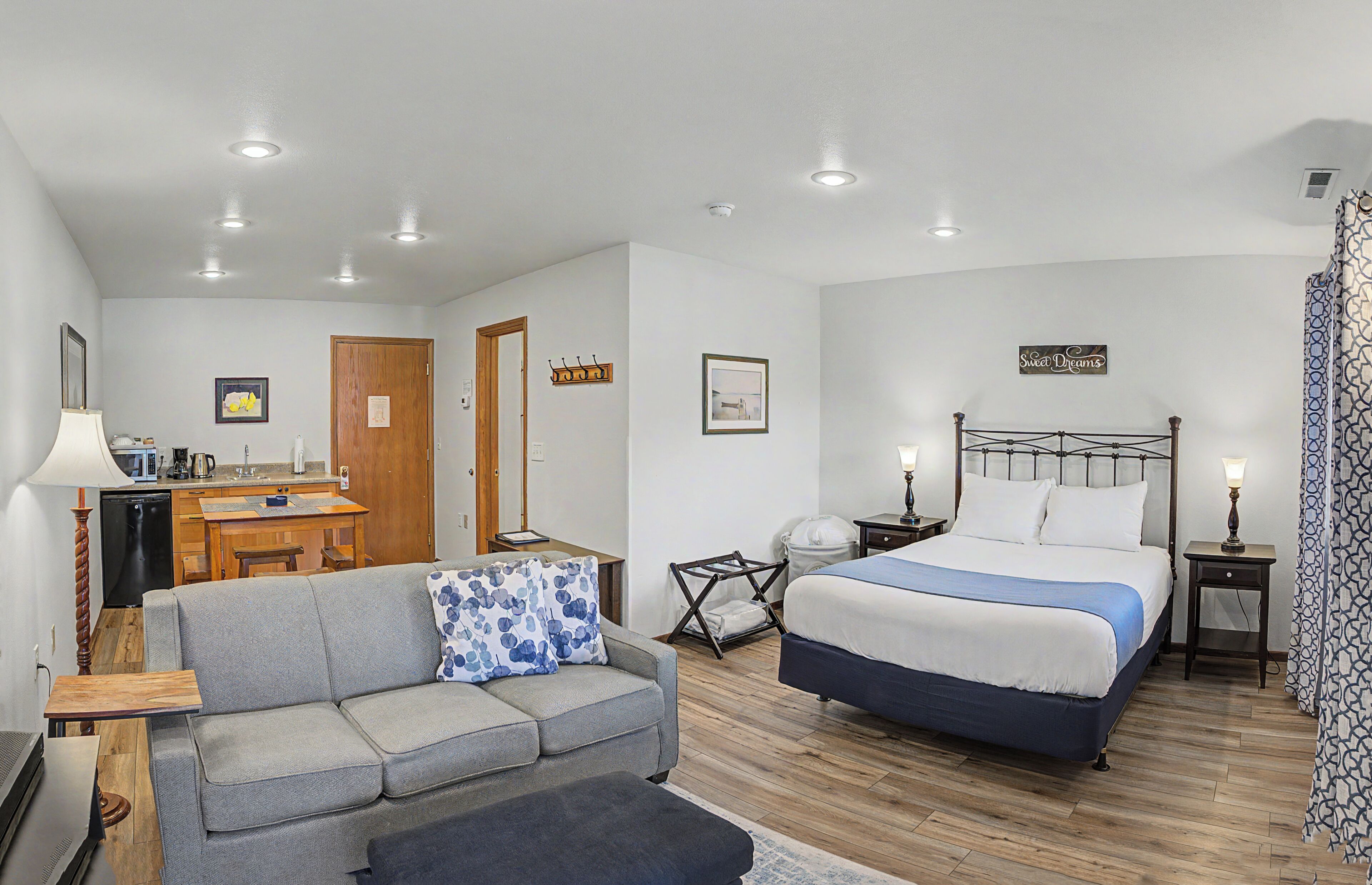Quarto com cama, sofá, escrivaninha e cozinha compacta.