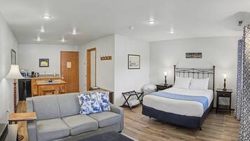 Quarto com cama, sofá, escrivaninha e cozinha compacta.