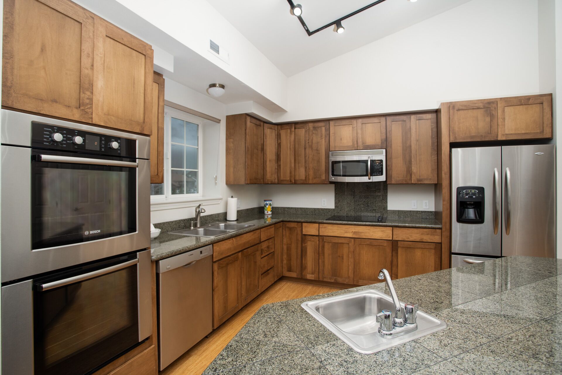 A modern kitchen with wooden cabinets, stainless steel appliances, and granite countertops.