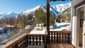 A balcony with a metal chair, overlooking a snow-covered landscape with mountains and a river. - Obertal Inn (Leavenworth)