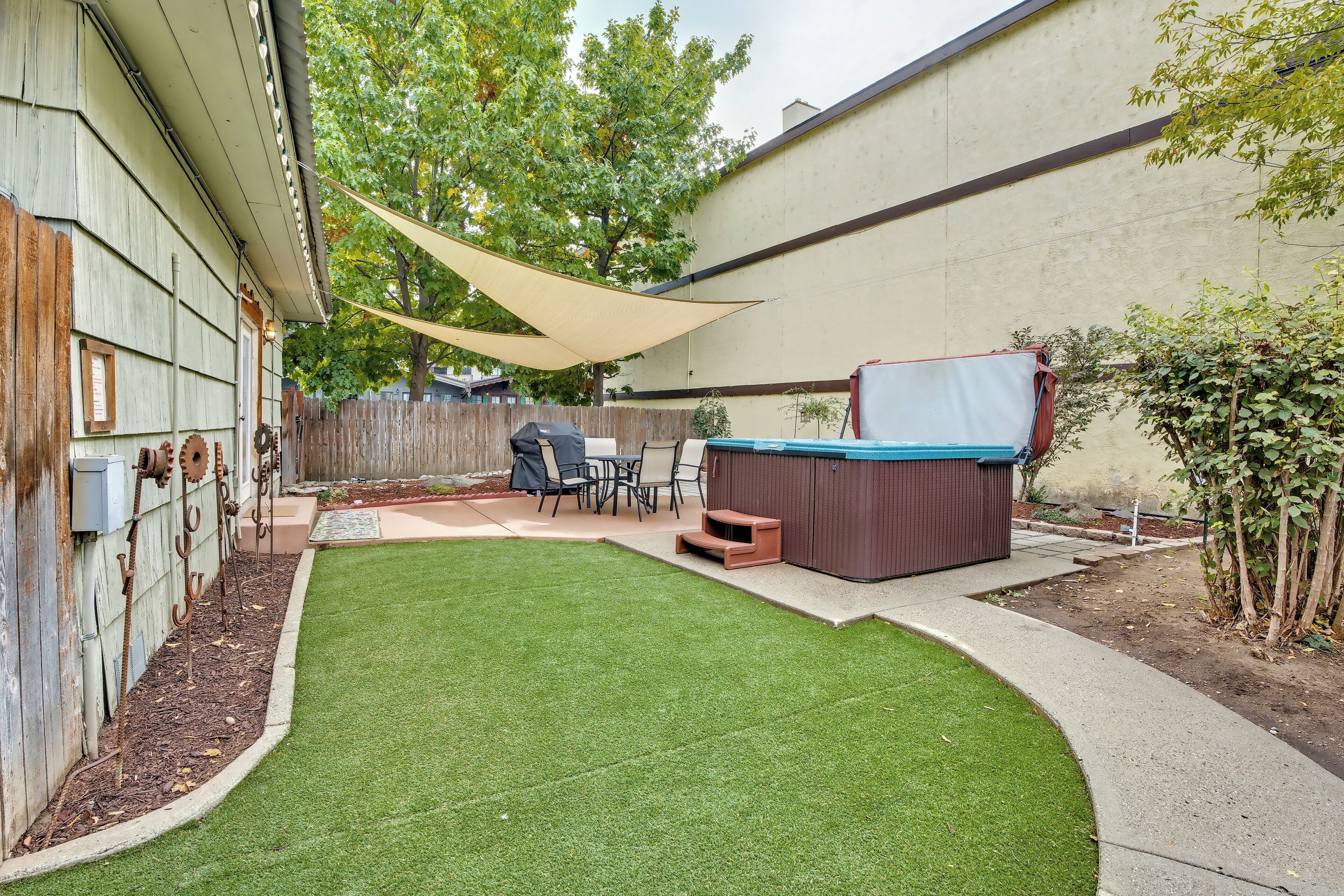 A backyard with artificial grass, a hot tub, and outdoor furniture.