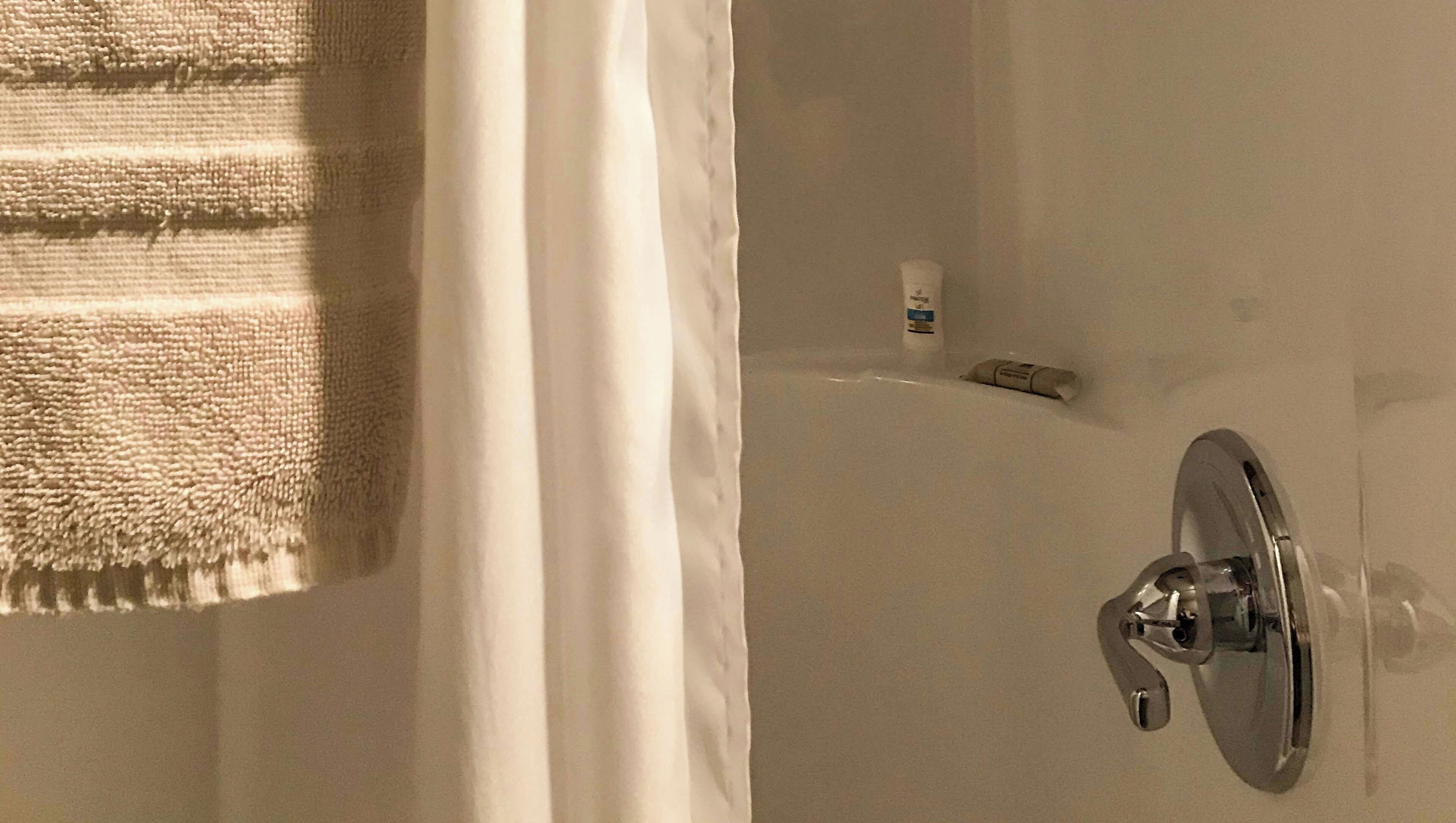 A bathroom with a bathtub, a towel, and a bottle of shampoo.