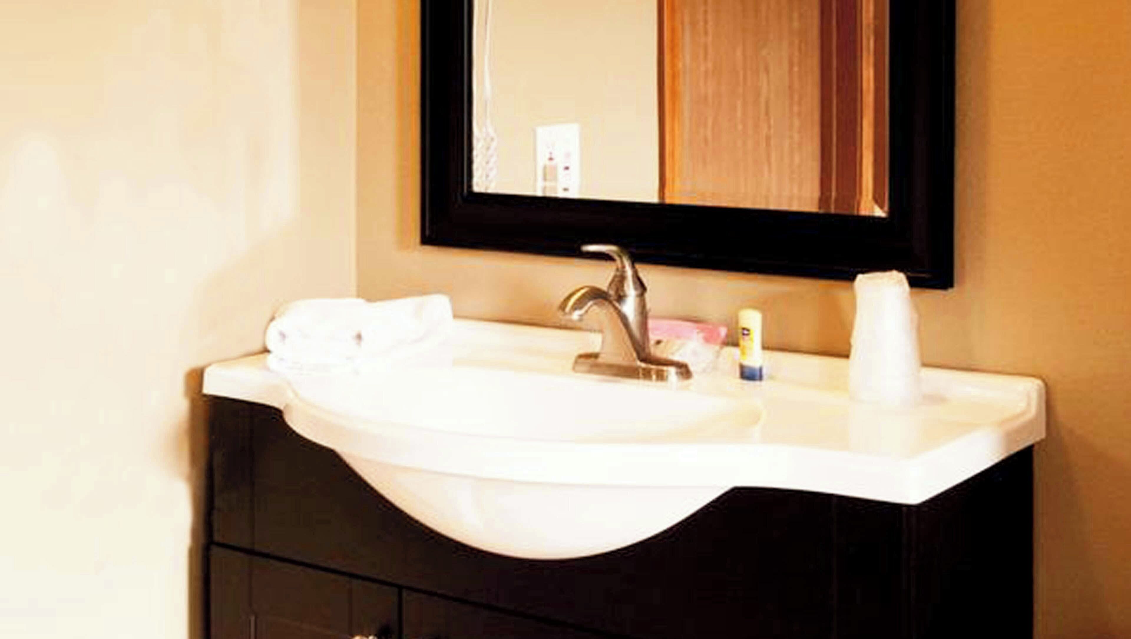Un lavabo de salle de bain avec un miroir, une serviette et un flacon de lotion.