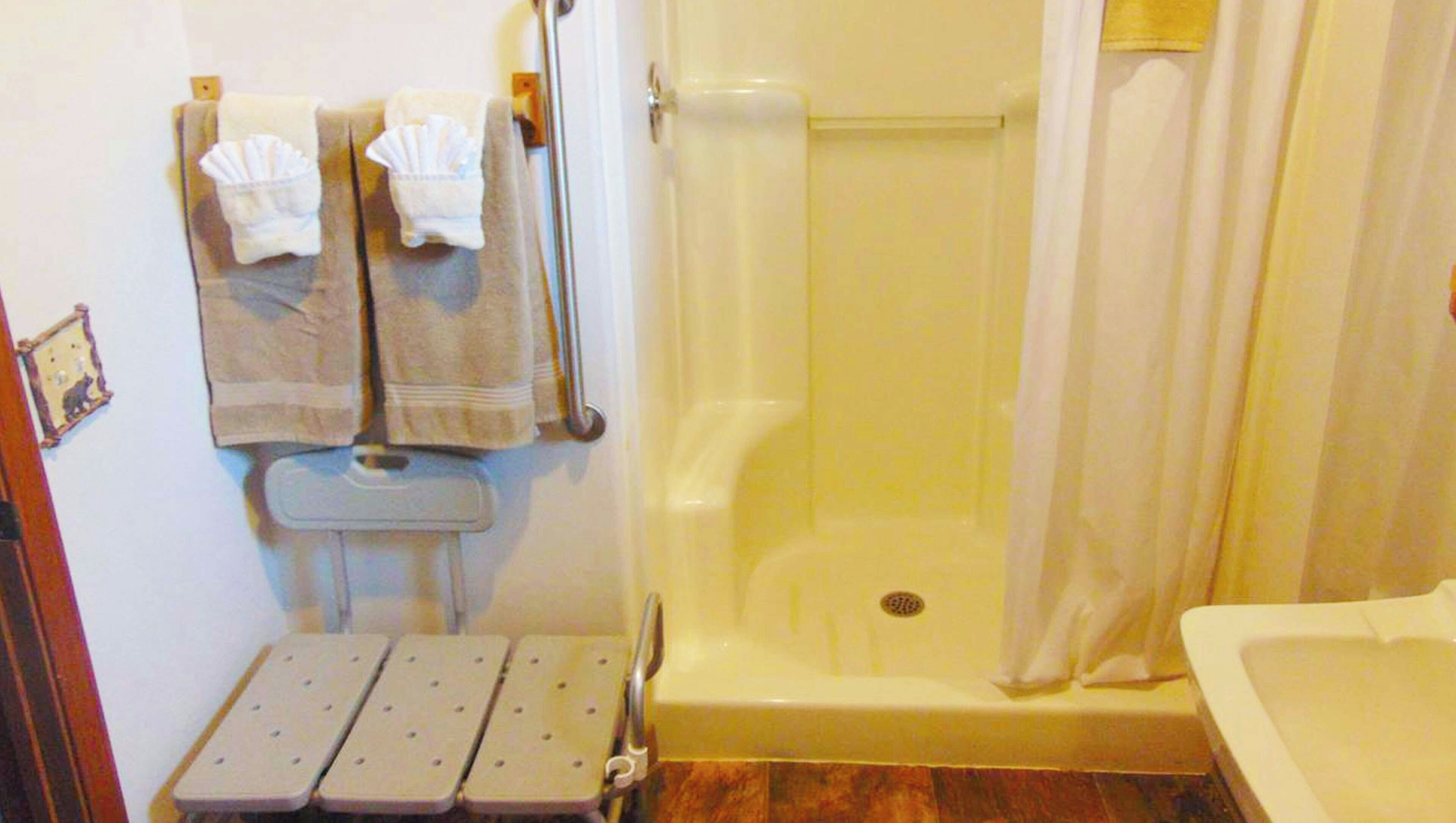 A bathroom with a shower, toilet, and a grab bar.