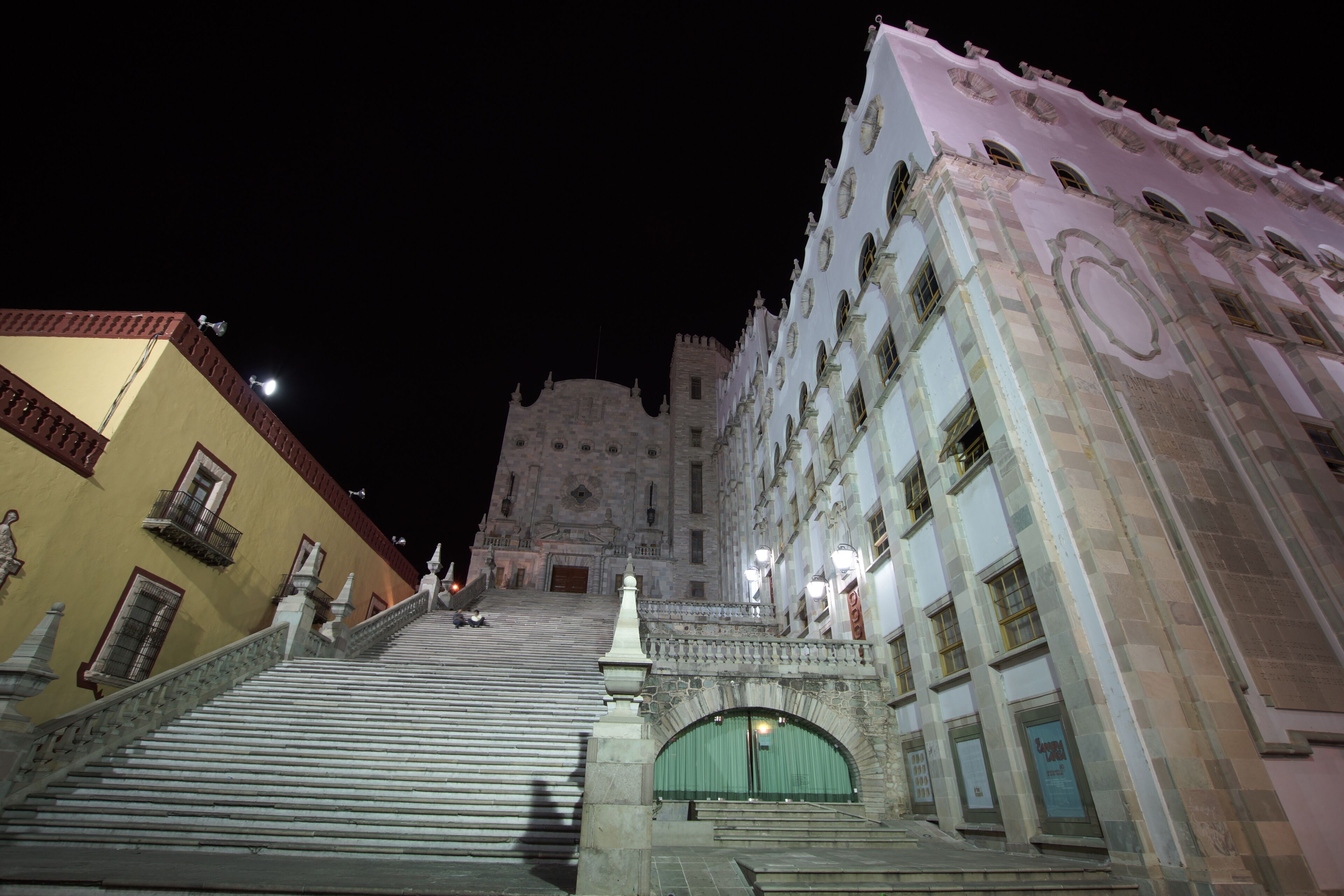 A grand staircase leading to a historic building with ornate architecture and a large arched entrance.