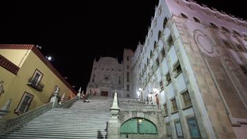 A grand staircase leading to a historic building with ornate architecture and a large arched entrance.