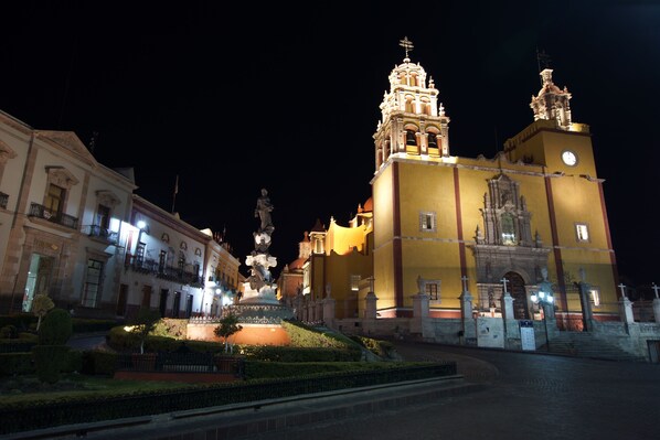 Un edificio histórico con una destacada torre campanario y una estatua en la parte frontal.