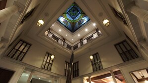 Un vaste atrium agrémenté d’une grande baie vitrée aux motifs colorés, de nombreux balcons et de détails architecturaux classiques.