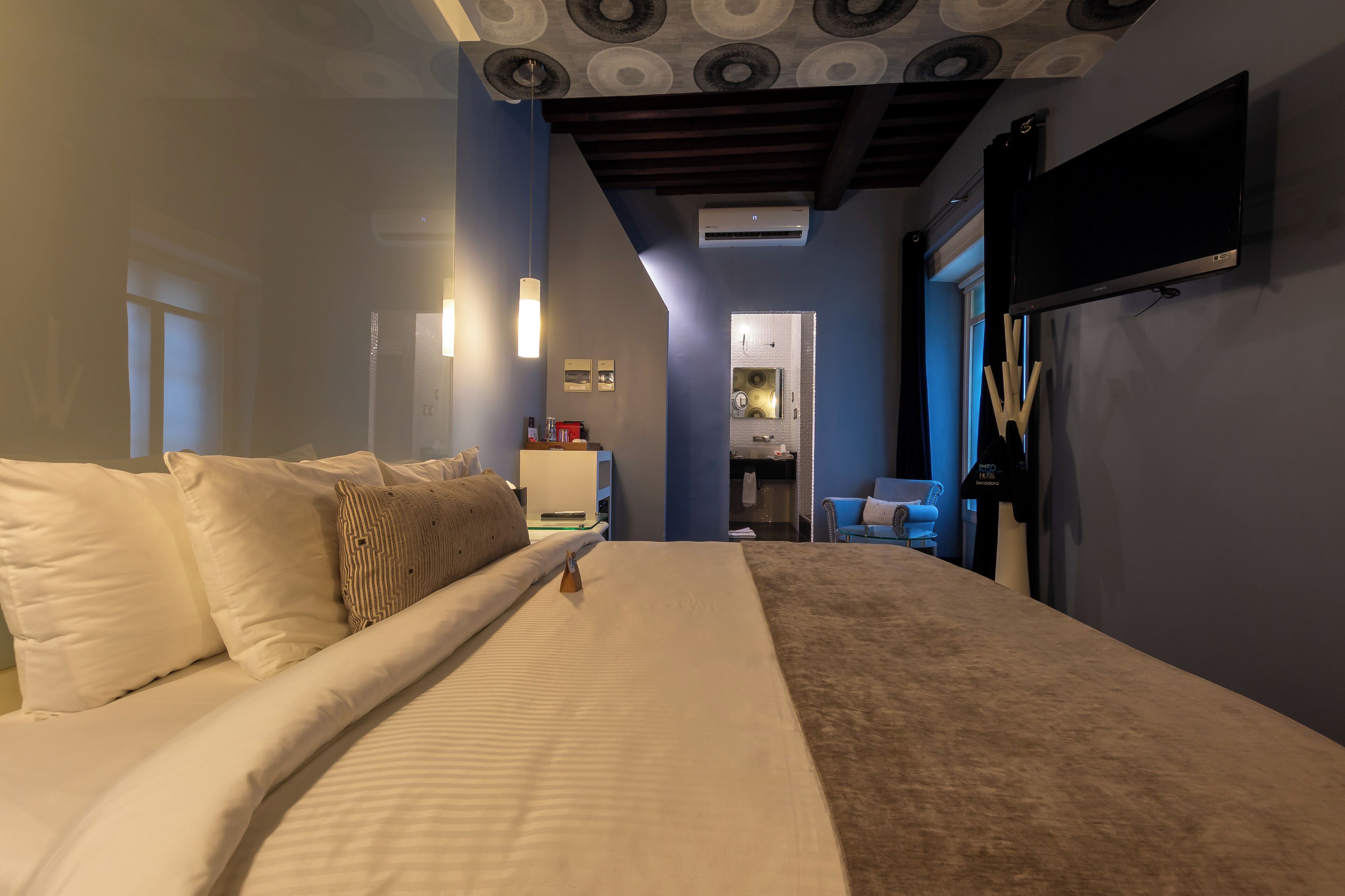 Un dormitorio con una cama grande, un televisor de pantalla plana montado en la pared y un techo con diseños circulares.