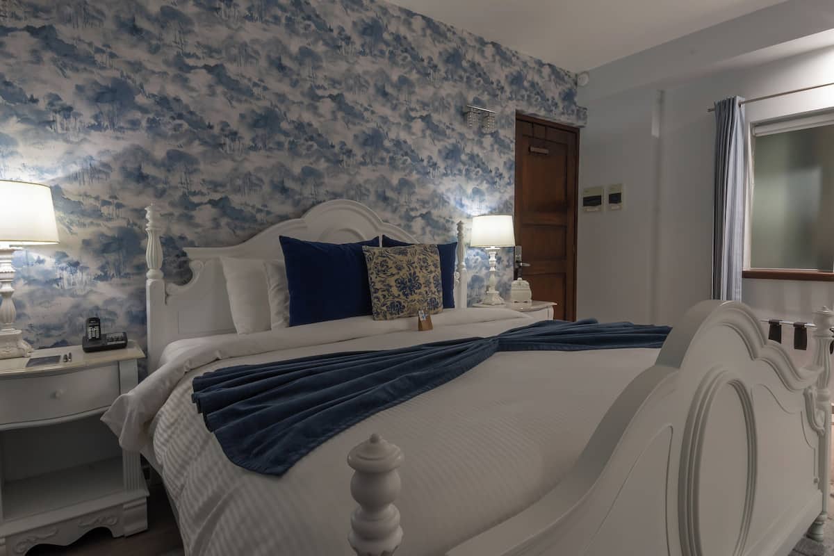 Un dormitorio con cama, mesitas de noche y ventana.