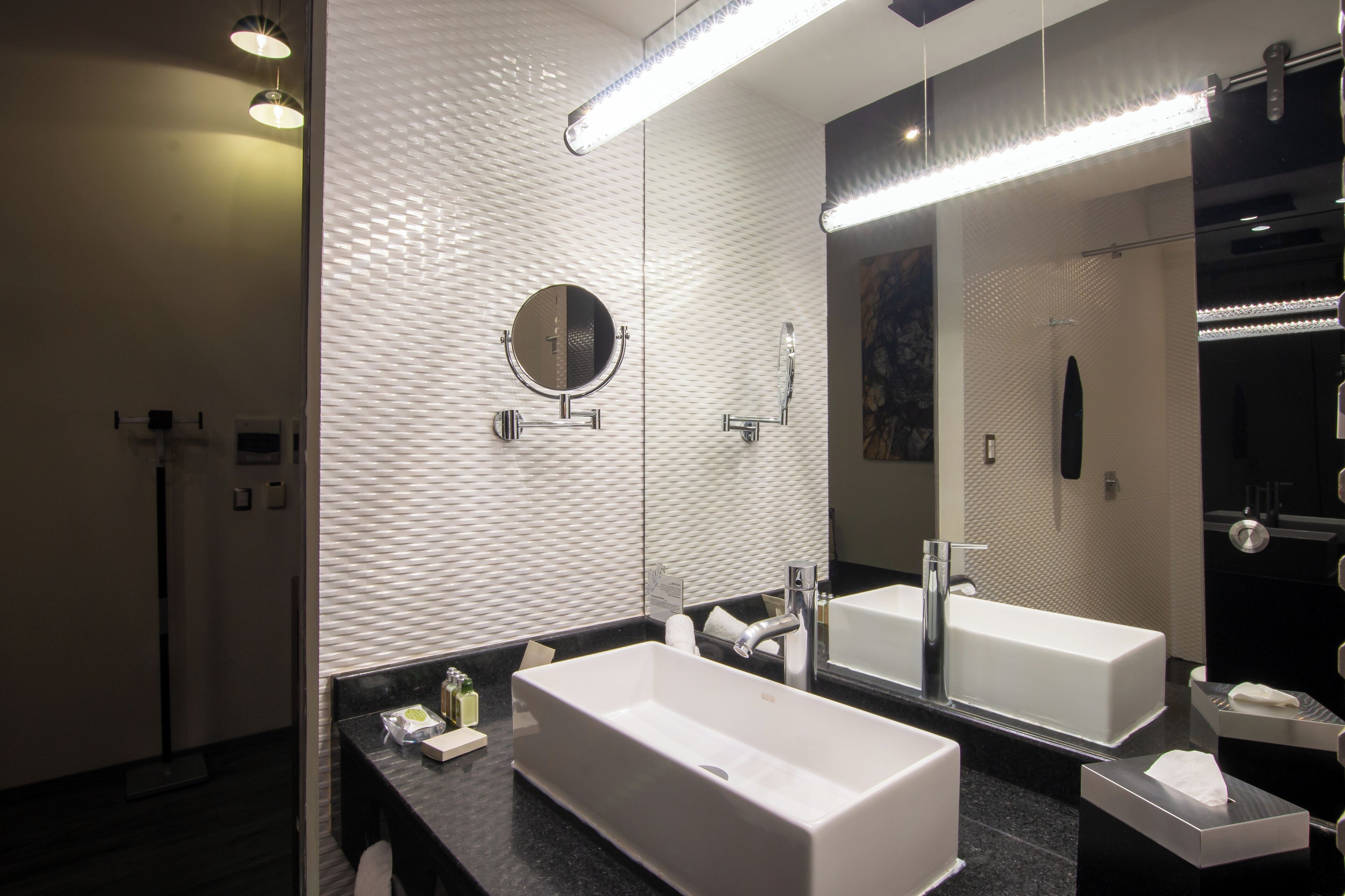 Un bagno moderno con uno specchio grande, due lavabi e una zona doccia.