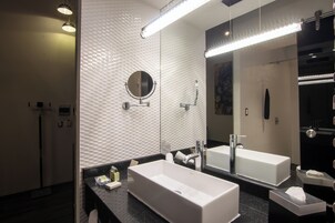 Un baño moderno con un espejo grande, dos lavamanos y una zona de ducha.